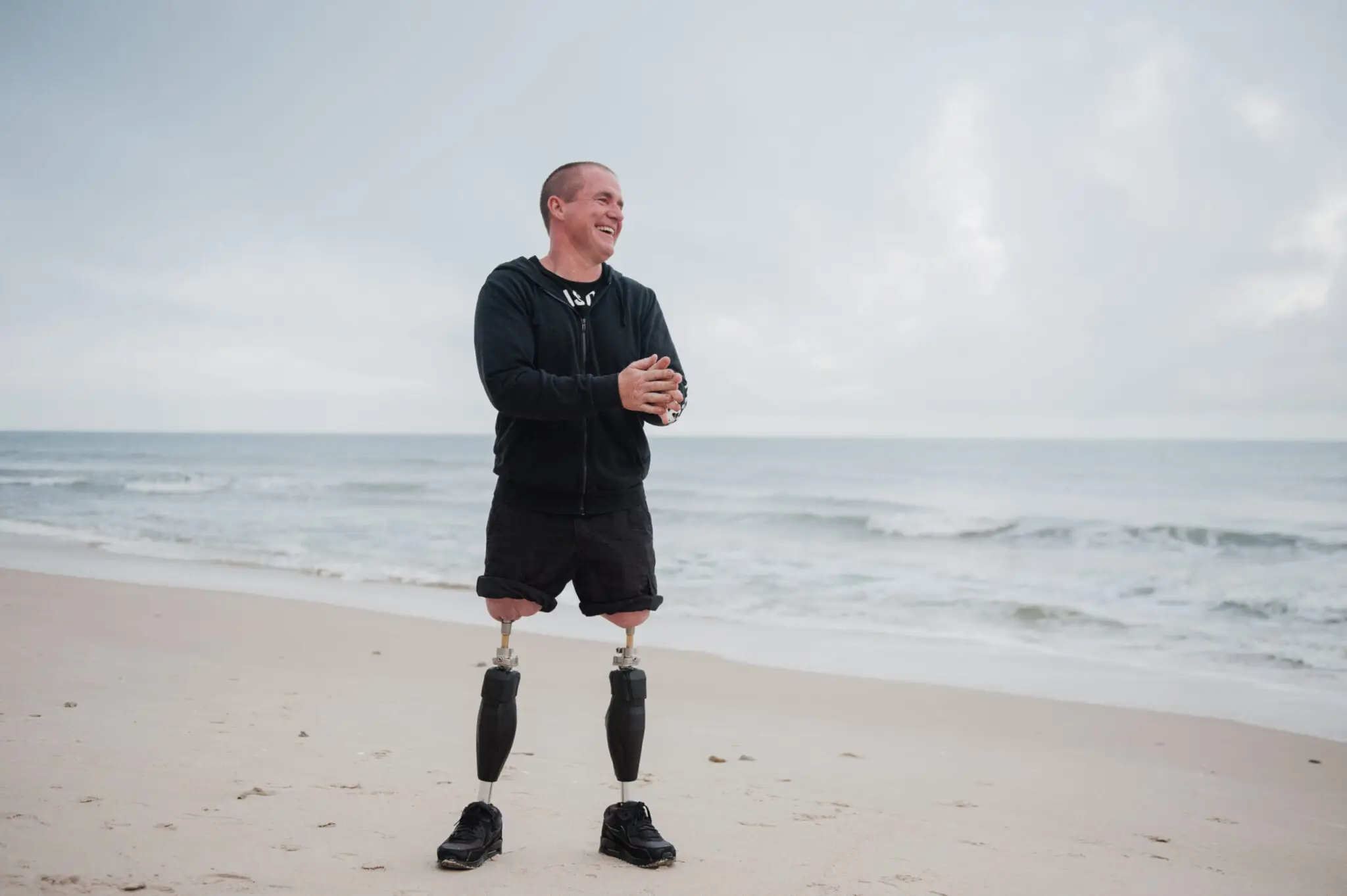 A bilateral amputee with osseointegrated prosthetic legs standing on a beach